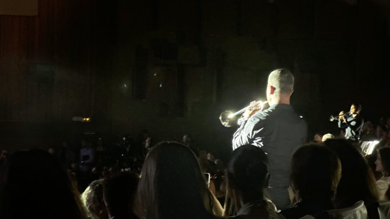Un trompettiste joue au milieu du public, pris dans un faisceau de lumière, pendant la cérémonie d’ouverture du festival Manaki 2026